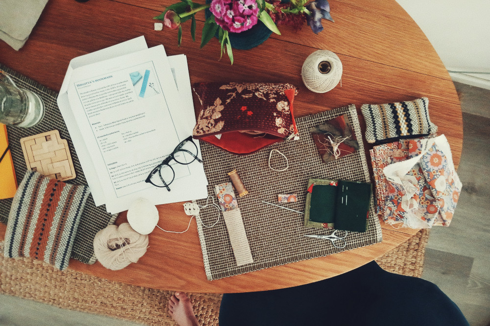 A horizontal colour photograph of a messy table full of sewing and crochet kit and small projects.