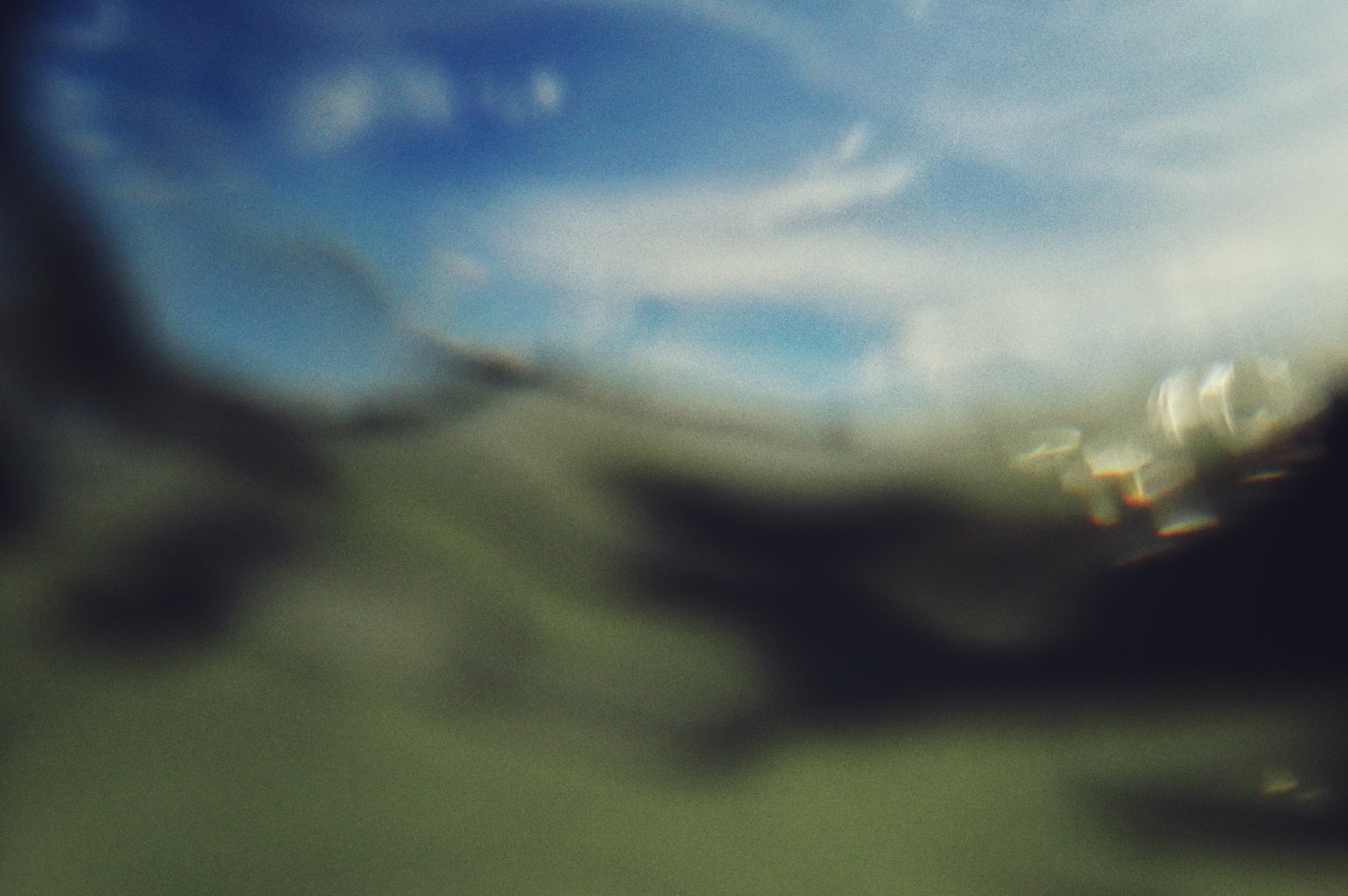 A horizontal colour photograph of moving water. The image is blurred. The water is curved and green. Above is the blue of sky and trails of wispy white clouds.